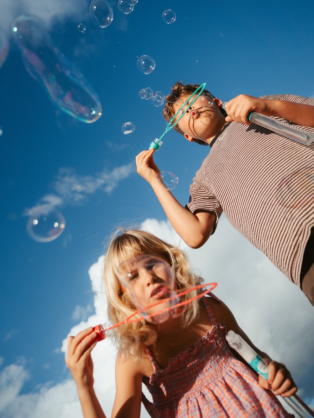 Ragazzi che soffiano bolle di sapone contro il cielo azzurro