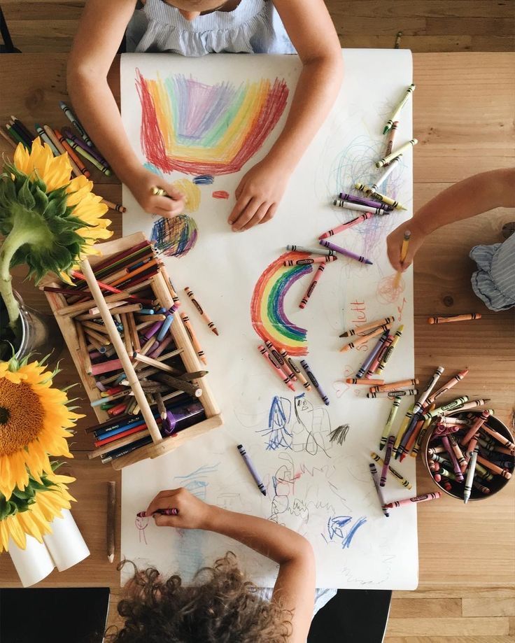 Bambini che disegnano con i pastelli a cera attorno a un tavolo